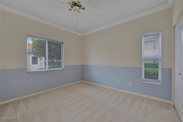 carpeted spare room featuring ornamental molding, a wealth of natural light, and ceiling fan