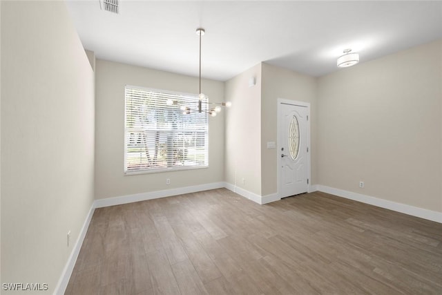 unfurnished room featuring an inviting chandelier and wood-type flooring