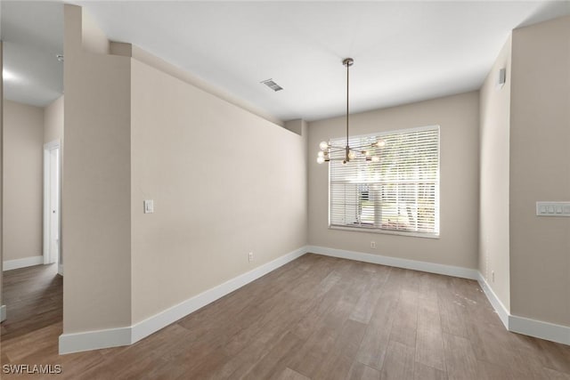 unfurnished room with a chandelier and light wood-type flooring