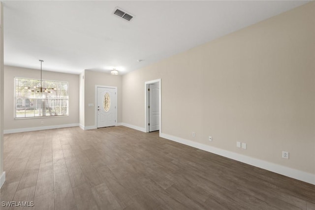 unfurnished room featuring hardwood / wood-style flooring and a notable chandelier