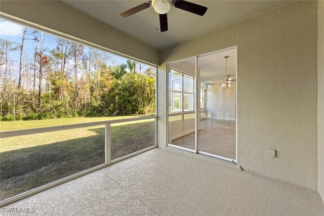 unfurnished sunroom featuring ceiling fan and a healthy amount of sunlight