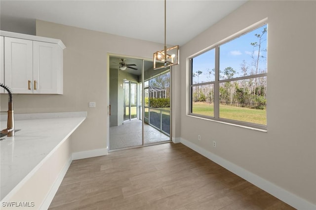 unfurnished dining area featuring a chandelier and light wood-type flooring