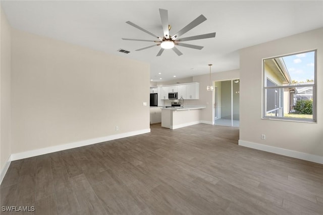 unfurnished living room featuring sink, dark wood-type flooring, and ceiling fan