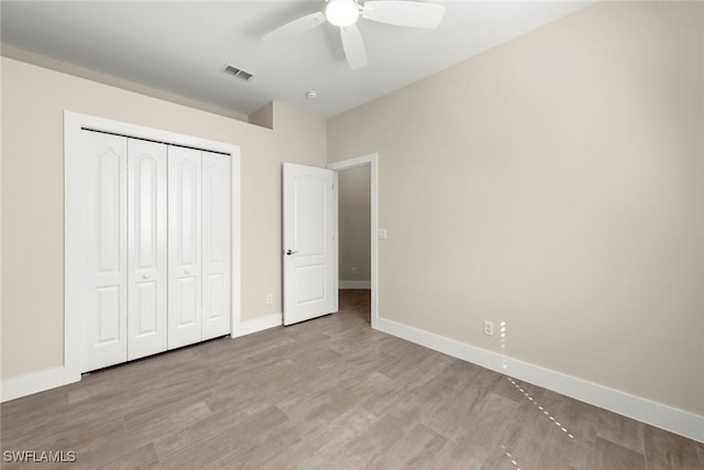 unfurnished bedroom with light hardwood / wood-style floors, ceiling fan, and a closet