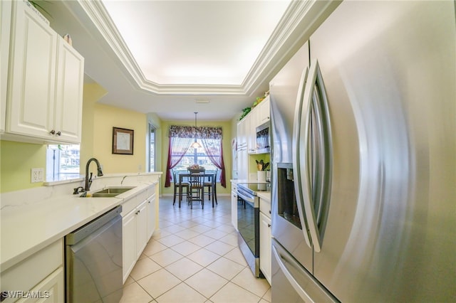 kitchen featuring decorative light fixtures, a raised ceiling, white cabinetry, sink, and stainless steel appliances