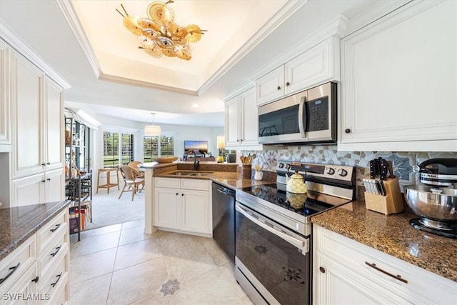 kitchen featuring sink, appliances with stainless steel finishes, a raised ceiling, pendant lighting, and white cabinets