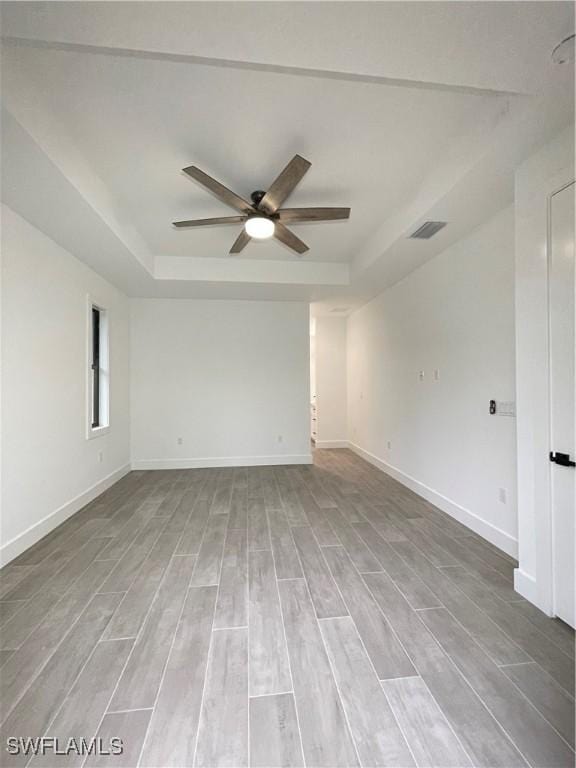 unfurnished room featuring hardwood / wood-style floors, ceiling fan, and a tray ceiling