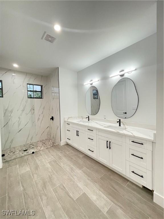 bathroom with vanity and a tile shower