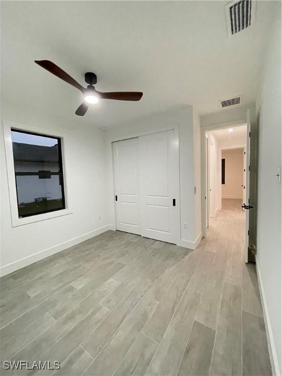 unfurnished bedroom featuring light hardwood / wood-style floors, a closet, and ceiling fan