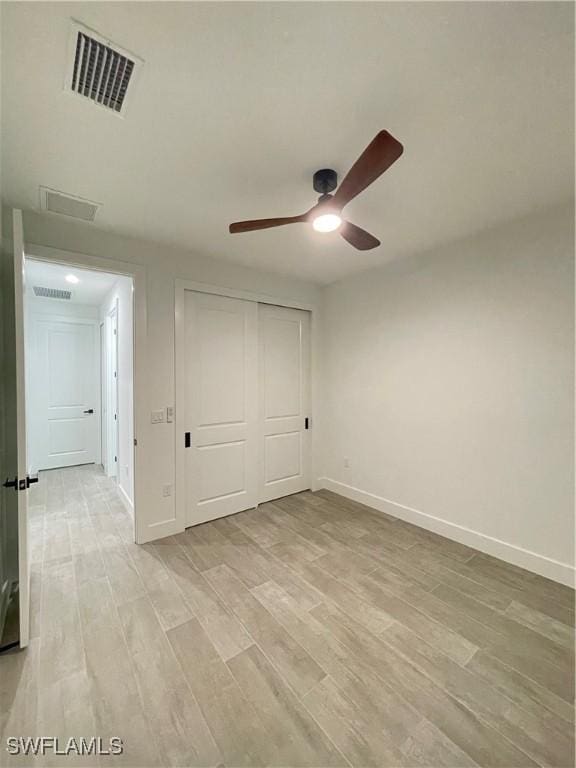 unfurnished bedroom with light hardwood / wood-style floors, ceiling fan, and a closet