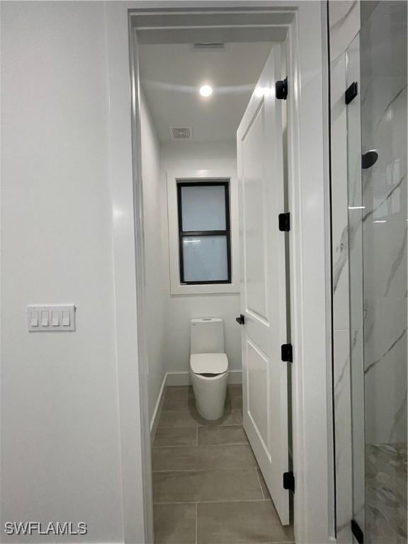 bathroom with a shower with shower door and toilet