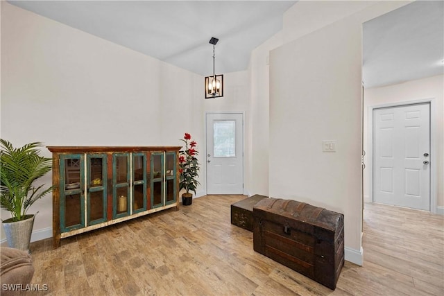 foyer entrance featuring baseboards, an inviting chandelier, and wood finished floors