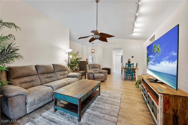 living room featuring track lighting, light wood-style flooring, ceiling fan, and vaulted ceiling