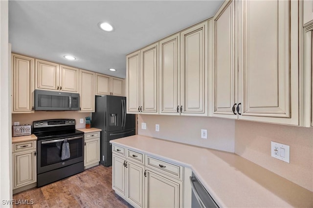 kitchen featuring light countertops, cream cabinets, black fridge with ice dispenser, and range with electric stovetop