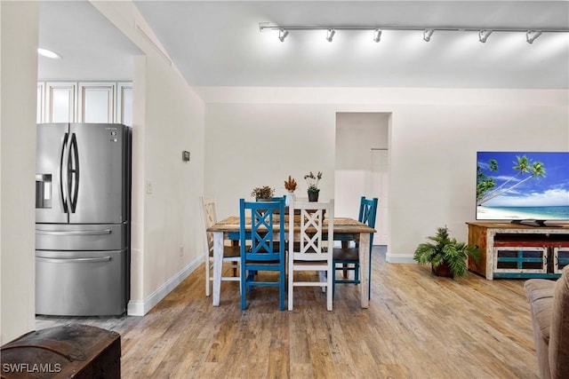 dining room with rail lighting, wood finished floors, and baseboards