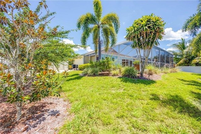 view of yard with glass enclosure and fence