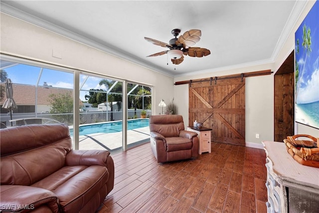 living room featuring dark wood-style floors, a barn door, crown molding, baseboards, and ceiling fan