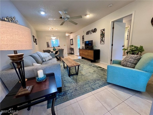 living room featuring tile patterned flooring, ceiling fan, and a textured ceiling