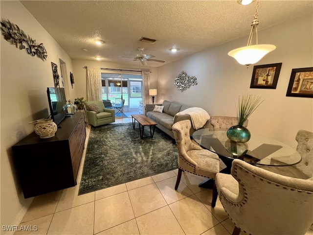 living room featuring ceiling fan, light tile patterned floors, and a textured ceiling