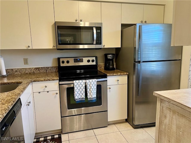 kitchen with light tile patterned floors, sink, stone counters, stainless steel appliances, and white cabinets