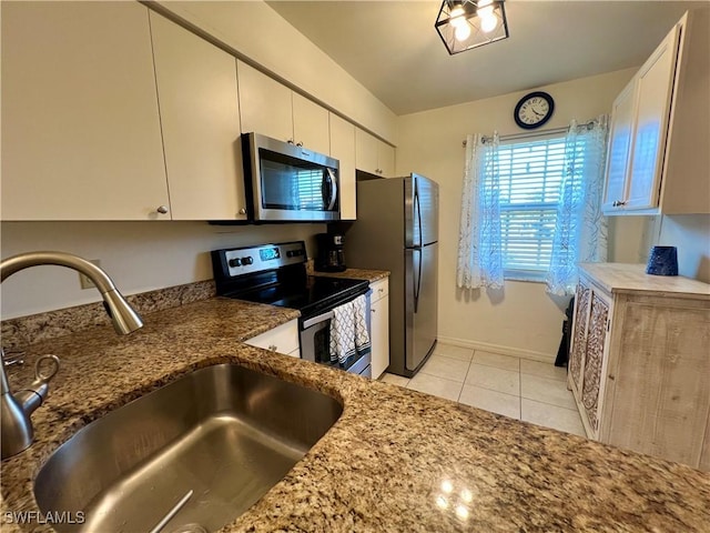 kitchen featuring sink, white cabinetry, light tile patterned floors, appliances with stainless steel finishes, and stone counters