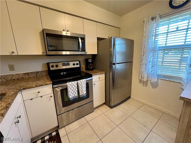 kitchen featuring stainless steel appliances, white cabinetry, plenty of natural light, and light tile patterned floors