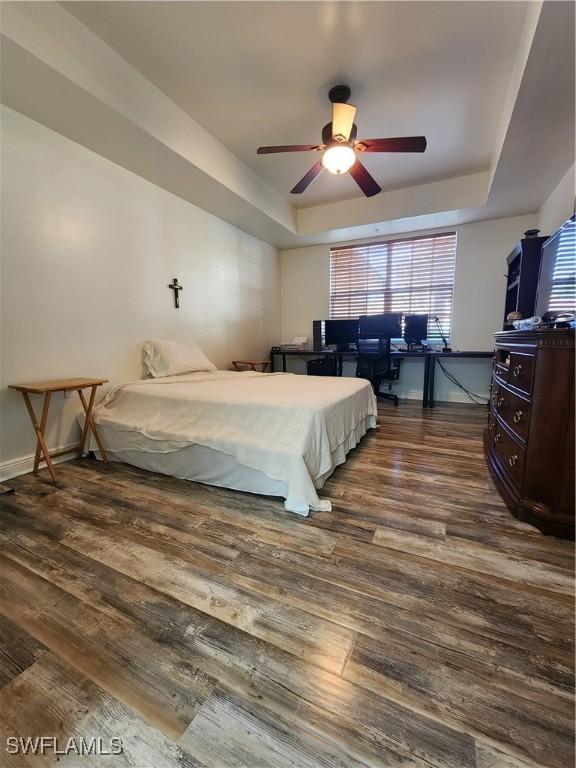 bedroom featuring ceiling fan, dark hardwood / wood-style floors, and a raised ceiling