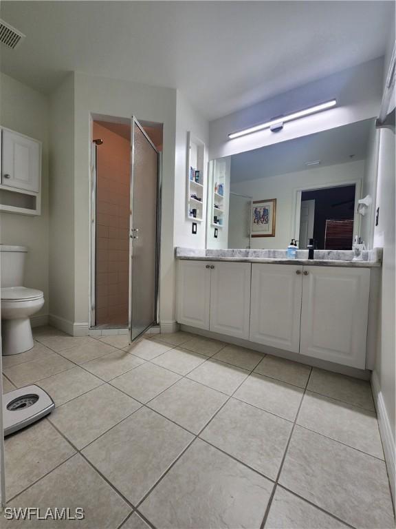 bathroom with tile patterned flooring, vanity, walk in shower, toilet, and built in shelves