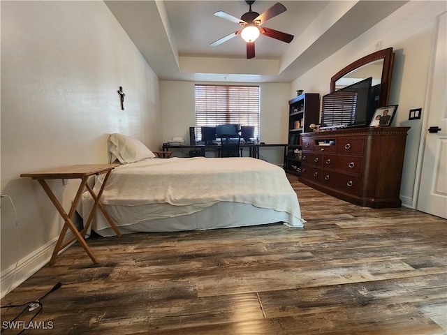 bedroom with a raised ceiling, hardwood / wood-style flooring, and ceiling fan