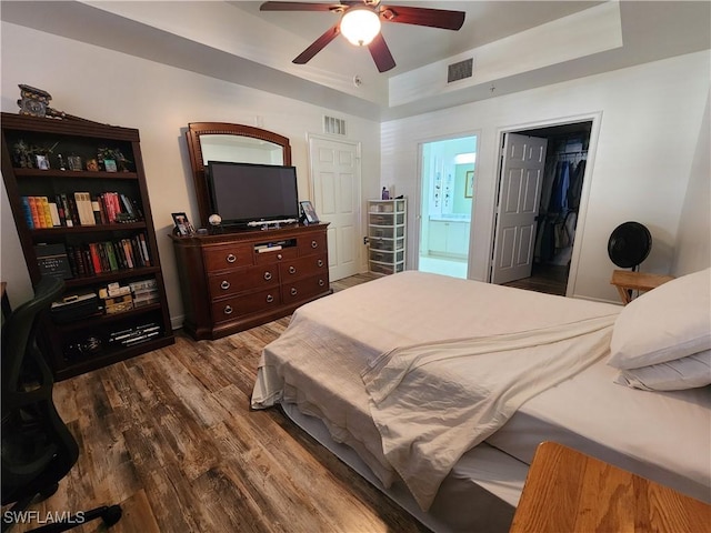 bedroom featuring wood-type flooring, a walk in closet, ceiling fan, ensuite bath, and a closet