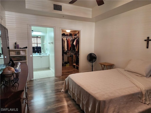 bedroom with ensuite bathroom, dark hardwood / wood-style floors, a spacious closet, ceiling fan, and a closet