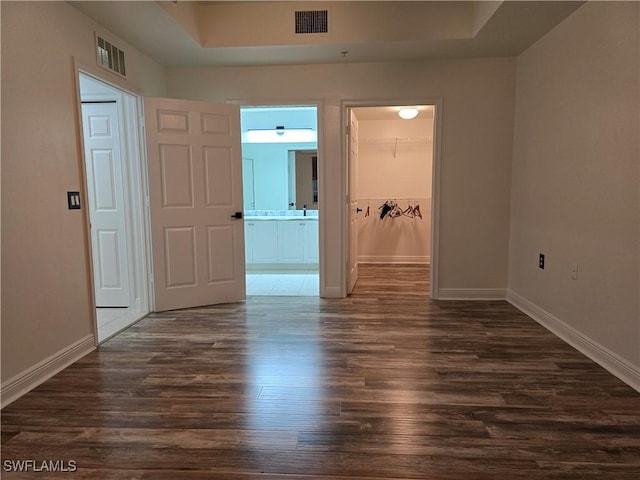 spare room featuring a tray ceiling and dark hardwood / wood-style floors