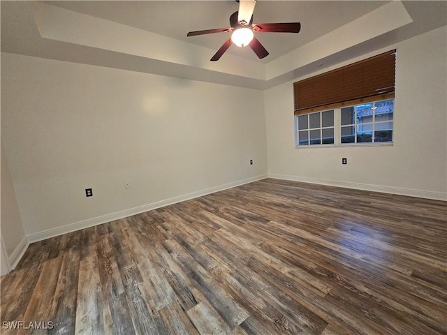 spare room featuring dark hardwood / wood-style floors, ceiling fan, and a tray ceiling