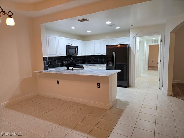 kitchen with white cabinetry, light tile patterned floors, kitchen peninsula, black fridge, and electric stove