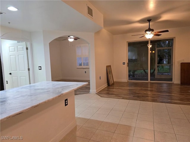 interior space featuring light tile patterned flooring, ceiling fan, and light stone countertops