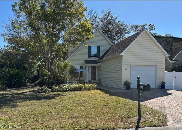 view of front of house with a front lawn, fence, decorative driveway, a garage, and a gate