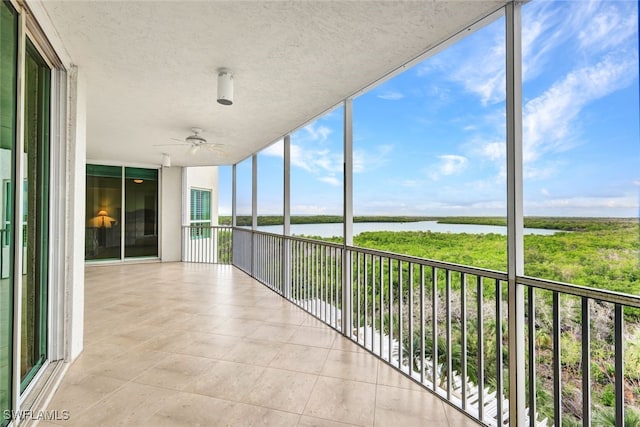 unfurnished sunroom with a water view, plenty of natural light, and ceiling fan