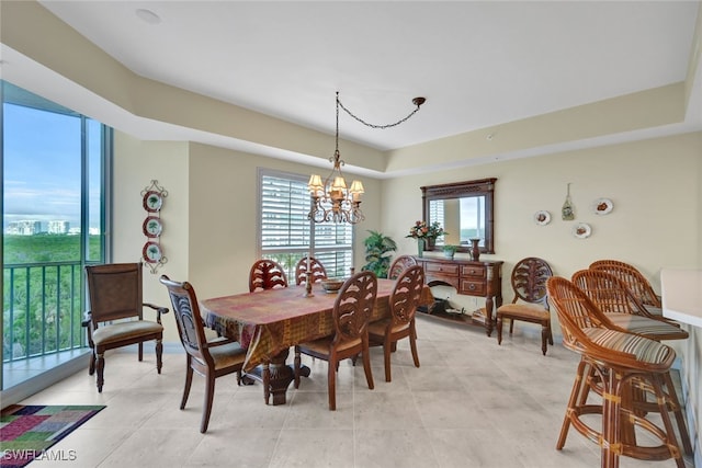 dining area featuring a raised ceiling, a wealth of natural light, and an inviting chandelier