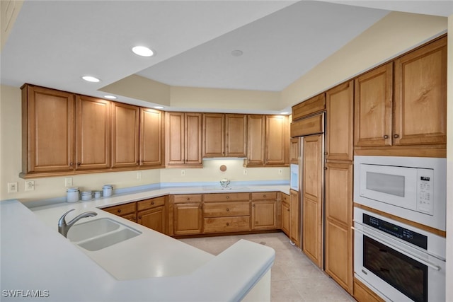 kitchen featuring sink, white appliances, kitchen peninsula, and light tile patterned floors