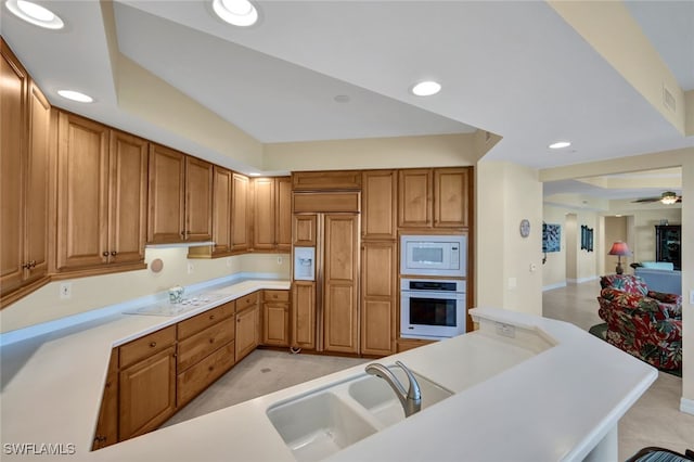 kitchen with built in appliances, sink, and ceiling fan