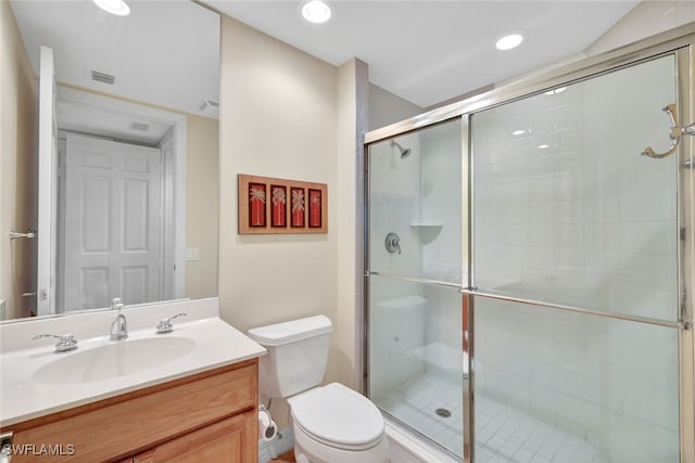 bathroom with vanity, a shower with door, and toilet