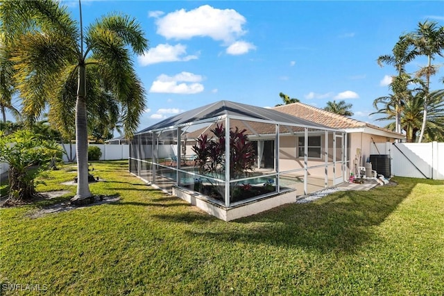 rear view of house with a yard, a swimming pool, a patio, and glass enclosure