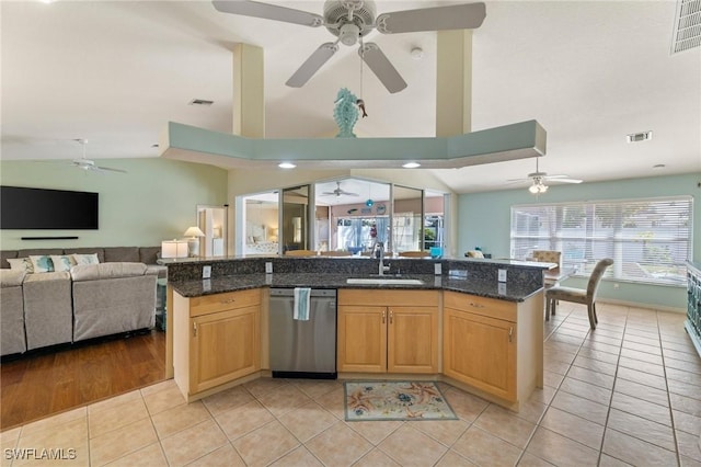 kitchen with sink, light tile patterned floors, dark stone countertops, a center island with sink, and stainless steel dishwasher