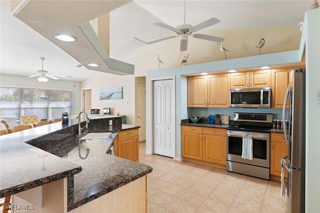 kitchen featuring vaulted ceiling, sink, dark stone countertops, light tile patterned floors, and stainless steel appliances