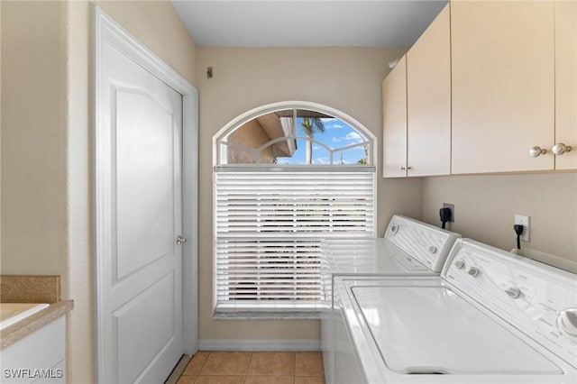 laundry area featuring light tile patterned floors, washer and clothes dryer, and cabinets