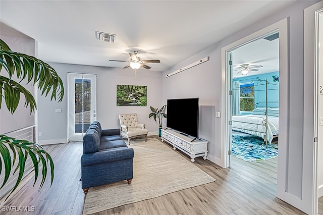 living room featuring a wealth of natural light, ceiling fan, and light hardwood / wood-style flooring