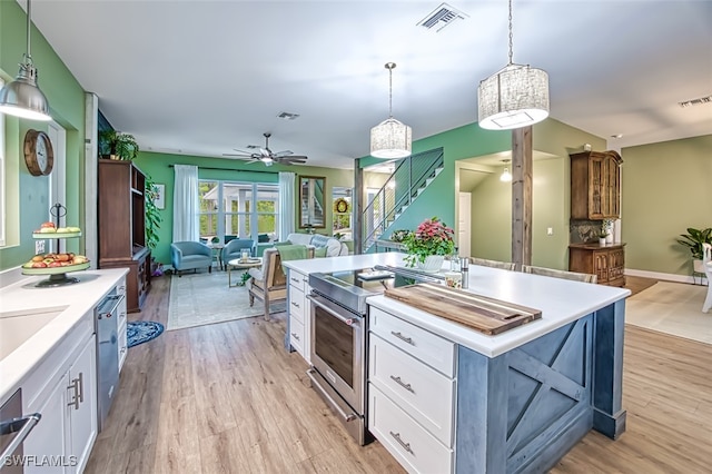 kitchen with pendant lighting, white cabinetry, stainless steel range with electric cooktop, a center island with sink, and light wood-type flooring