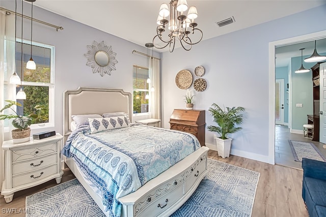 bedroom featuring an inviting chandelier and light hardwood / wood-style floors