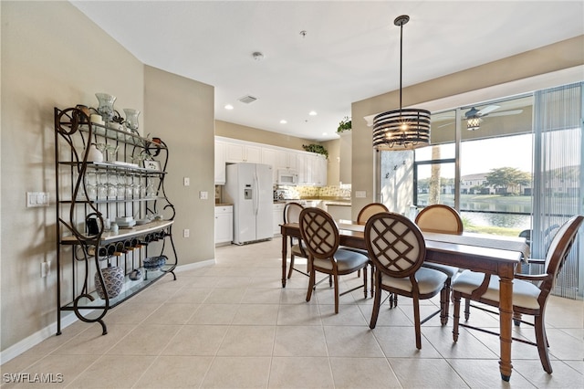 tiled dining space with ceiling fan and a water view