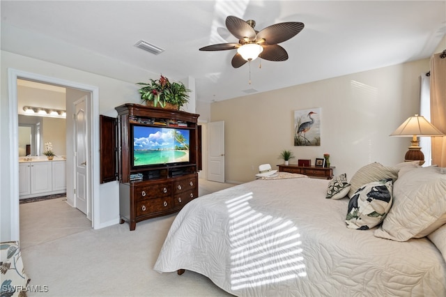 bedroom with connected bathroom, light colored carpet, and ceiling fan